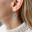 Model wearing a dainty gold filled turquoise dangle earring with a faceted turquoise briolette, December birthstone