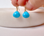 Hand holding gold filled turquoise dangle earrings above a marble dish