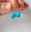 Turquoise dangle earrings held between fingers, showing the size of the faceted turquoise briolettes