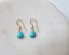 Dainty turquoise dangle earrings with wire-wrapped faceted stones on white marble