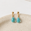 Dainty turquoise drop stud earrings in gold filled resting on a stone dish