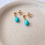 Gold filled turquoise stud earrings showing ball posts and butterfly backs on a speckled stoneware dish