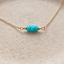Turquoise three-bead necklace in 14k gold-filled angled on a cream stone dish