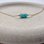 Low-angle view of three faceted turquoise beads with 14k gold-filled accent beads on a stone dish