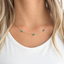 Model wearing a dainty gold filled turquoise station necklace with three turquoise beads spaced along a fine chain, December birthstone