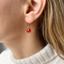 Model wearing a dainty carnelian heart drop earring in 14k gold-filled with an ivory turtleneck sweater