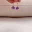 a model is shown holding a pair of amethsty drop earrings. The amethysts dangle from a simple, gold ear wire.