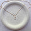 Close up of dainty 14k gold filled anchor charm necklace on ceramic dish