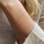 A dainty gold cable chain bracelet displayed on a model