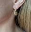 Model wearing a chunky gold croissant hoop earring with a twisted, ribbed dome design, front view