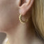 Gold filled croissant hoop earring on the ear, side view showing the tapered twisted hoop shape