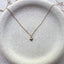 Close up of dainty 14k gold filled heart charm necklace on ceramic dish