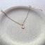 Close up of dainty 14k gold filled heart charm necklace on natural linen