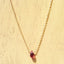Necklace with a red garnet teardrop pendant on a light wooden surface