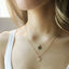 Two layered gold initial disc necklaces worn on a model, M pendant on a shorter chain and L pendant on a longer chain