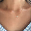 Dainty white opal teardrop necklace in gold filled worn on a model