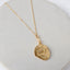 Greek Pegasus gold-filled medallion necklace displayed on pale stone