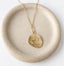 Greek Pegasus medallion necklace on pale stoneware dish