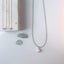 Long aquamarine necklace with pearl pendant styled alongside gemstone and delicate gold jewelry