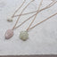 Close up flat lay of nature inspired charm necklaces showing mother of pearl star rose quartz feather and prehnite blossom