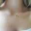 a dainty briolette peridot teardrop pendant on a dainty cable chain necklace is shown on a model