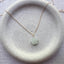 Close up of dainty 14k gold filled prehnite blossom charm necklace on ceramic dish