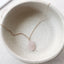 Dainty 14k gold filled rose quartz feather charm necklace on ceramic dish