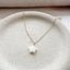 dainty star necklace in mother of pearl and gold filled shown flat on a stoneware dish with neutral fabric background