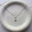 Close up of dainty 14k gold filled starfish charm necklace on ceramic dish